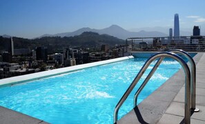A swimming pool with a metal ladder on a rooftop, overlooking a cityscape with mountains in the background. - Stunning Providencia Apt. with Pool (Providencia)