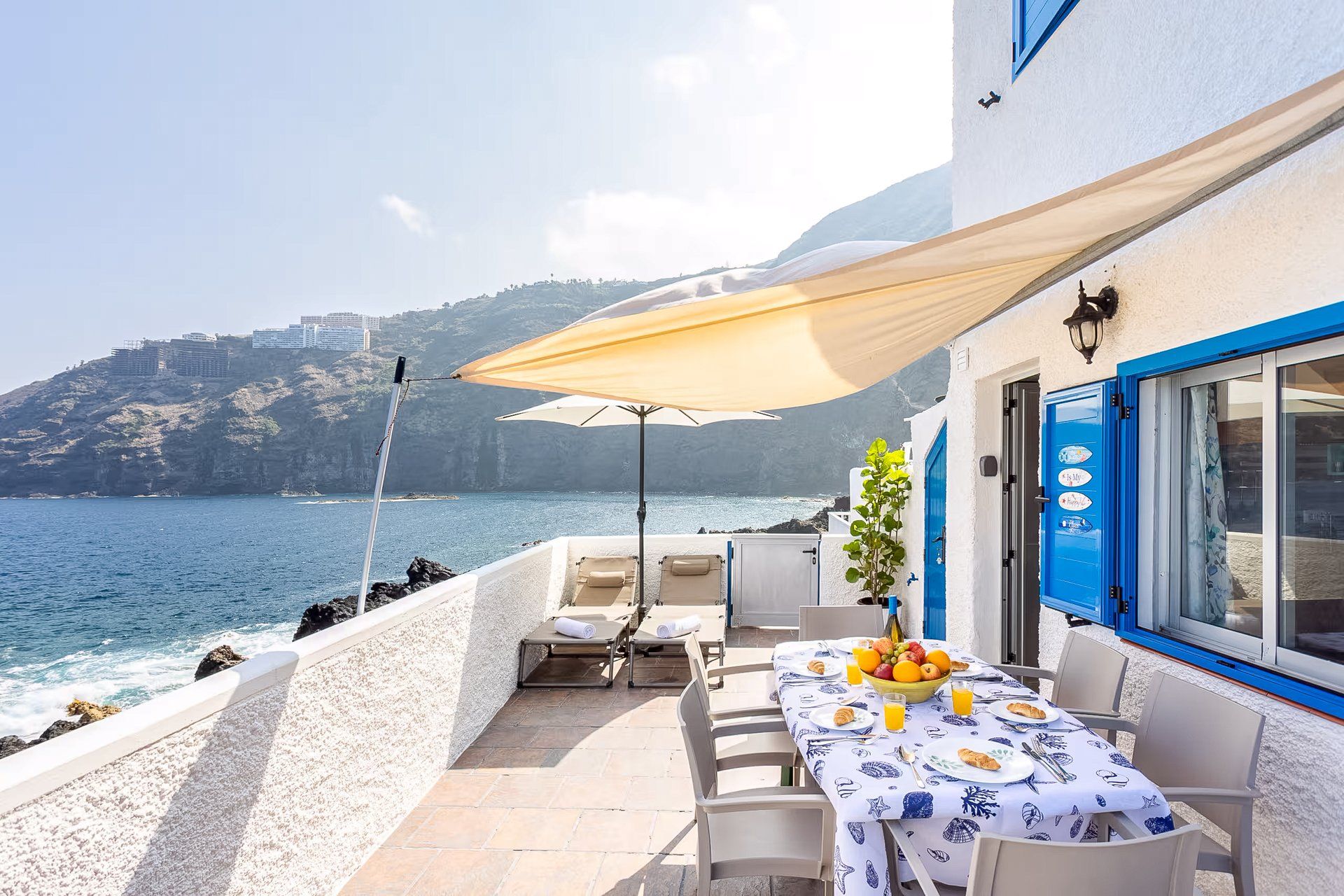 Eine Terrasse mit gedecktem Tisch für das Frühstück, mit Blick auf die Küste.