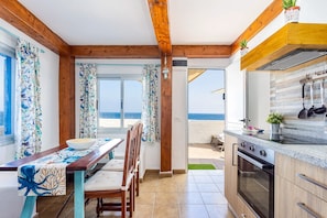 A coastal property with a dining area, kitchen, and a view of the beach. - GuestReady - Casa Lali in front El Caleton Pool (La Matanza de Acentejo)