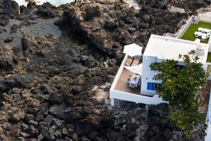 A white building with a terrace overlooking rocky terrain. - GuestReady - Casa Lali in front El Caleton Pool (La Matanza de Acentejo)