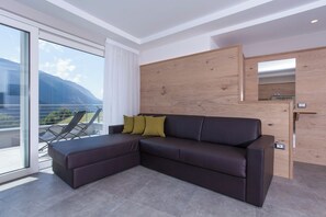 Ein modernes Wohnzimmer mit einem Ecksofa, einer Glastür, die auf einen Balkon führt, und einer Holzwandverkleidung.