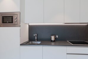 Eine moderne Küche mit eingebauter Mikrowelle, einem Edelstahl-Wasserkocher und einem eleganten Wasserhahn.