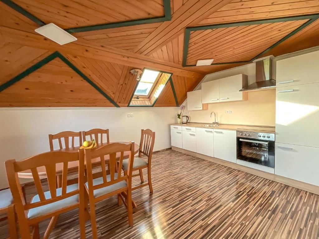 A kitchen with wooden flooring, white cabinets, and a skylight.
