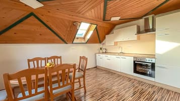 A kitchen with wooden flooring, white cabinets, and a skylight.