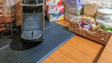 A kitchen counter with a coffee machine, boxes of tea, and a basket of snacks.