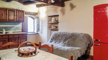A kitchen with wooden cabinets, a red refrigerator, and a dining table with a basket.