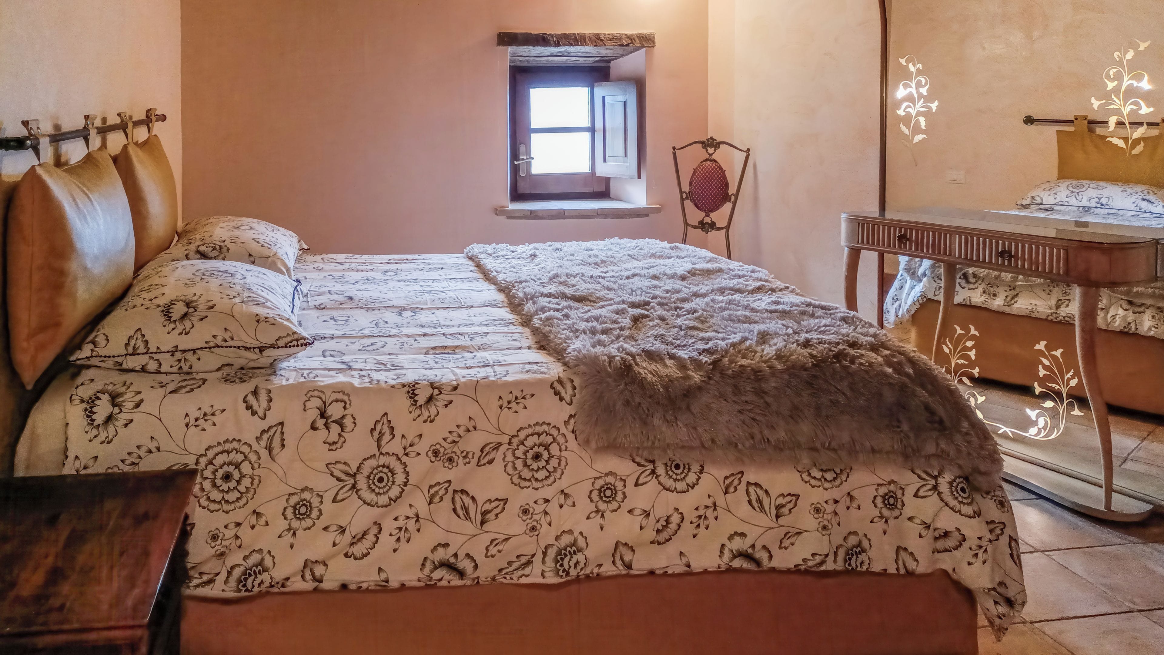 Une chambre à coucher avec un lit, une petite fenêtre, une chaise et une table.