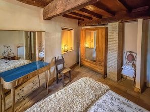 A room with a wooden table, a chair, a mirror, a bed, and a small window. - Domus Claudia (Castiglione In Teverina)