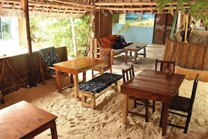 Eine Strandhütte mit Holzmöbeln und einem Reetdach.