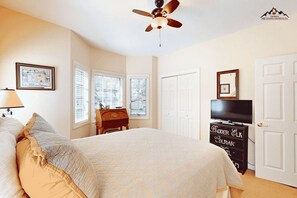 A bedroom with a bed, a dresser, a television, and a ceiling fan. - Luxury 2 Bedroom Sugar Mountain Condo with Gas Log Fireplace and Huge Deck (Sugar Mountain)