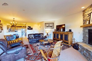 A spacious living room with a fireplace, a dining area, and a kitchen in the background. - Luxury 2 Bedroom Sugar Mountain Condo with Gas Log Fireplace and Huge Deck (Sugar Mountain)