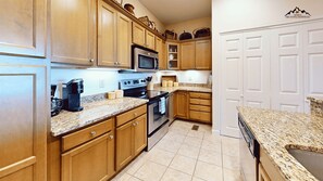 A kitchen with wooden cabinets, a microwave, an oven, and a coffee maker. - Luxury 2 Bedroom Sugar Mountain Condo with Gas Log Fireplace and Huge Deck (Sugar Mountain)