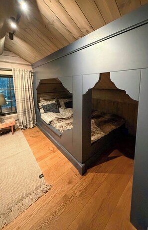 A bedroom with a bunk bed, wooden flooring, a window with curtains, and a bedside table. - Log cabin with jacuzzi and Gaustatoppen views (Tinn Austbygd)