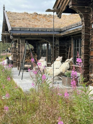 A log cabin with a porch, a swing, and a dog. - Log cabin with jacuzzi and Gaustatoppen views (Tinn Austbygd)