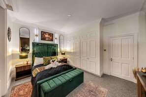 Een slaapkamer met een groot bed, nachtkastjes, een spiegel, een schilderij en een kledingkast.
