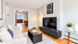 A modern living room with a sofa, coffee table, and a flat-screen TV. - Private Apt Walk to Shops/Restaurants (Boston, MA)