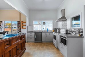 A modern kitchen with a dishwasher, oven, and a large window. - Expansive 6 Bedroom House. Fully fenced short walk to the River or Town Center (Tūrangi)