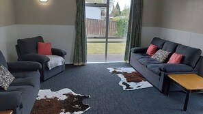 Een kamer met twee banken, een klein tafeltje en een kleden van koeienhuid.