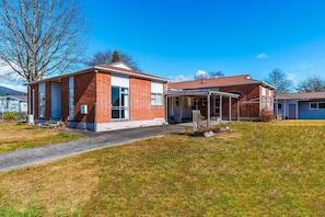 A two-story brick house with a covered porch and a front yard. - Expansive 6 Bedroom House. Fully fenced short walk to the River or Town Center (Tūrangi)