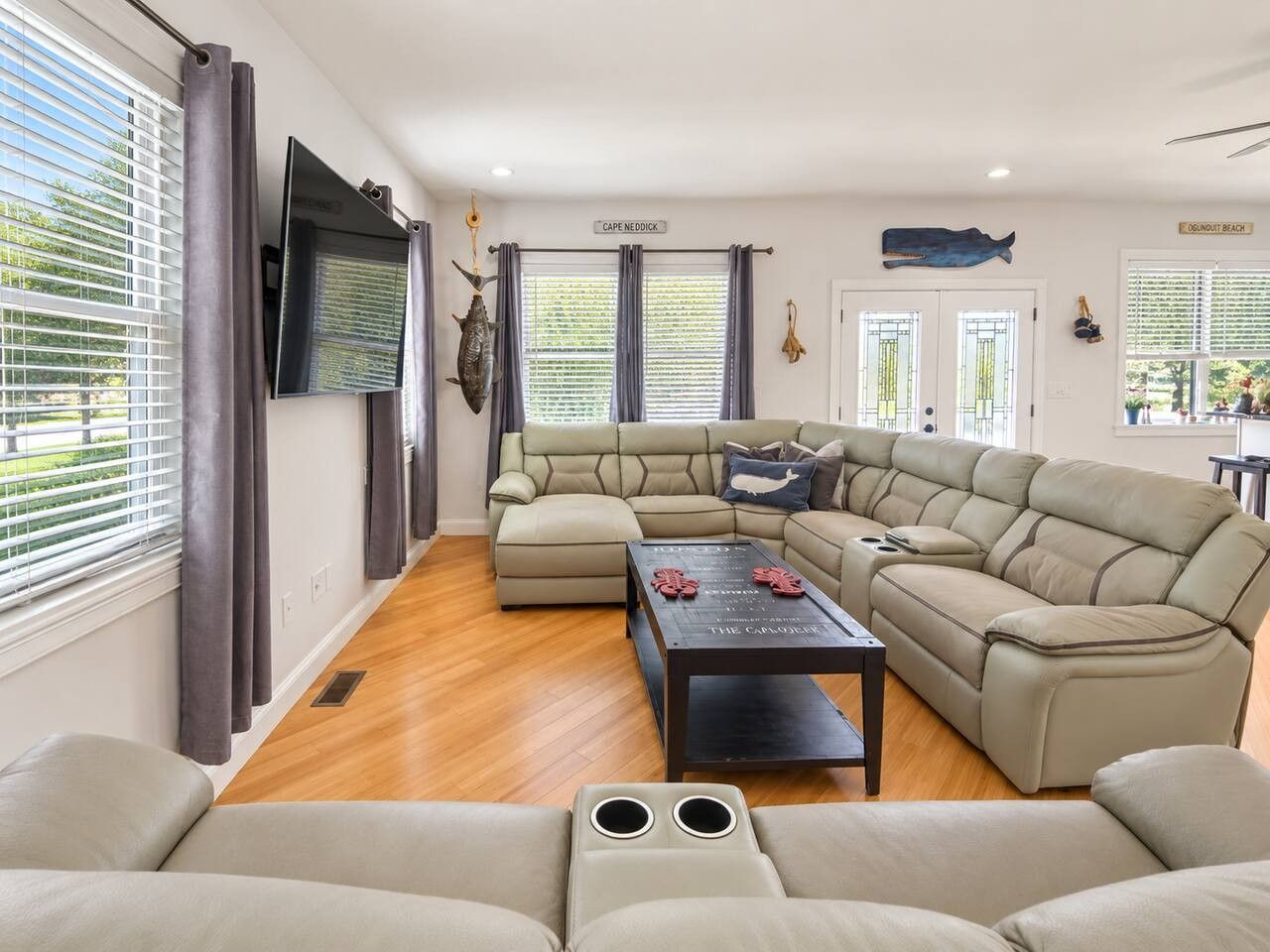 Una sala de estar amplia con un sofá modular, una mesa de centro y un televisor de pantalla plana montado en la pared.