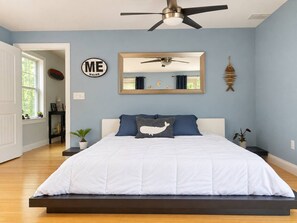 Ein Schlafzimmer mit einem Bett, einem Deckenventilator, einem Spiegel und einem Wandzeichen.