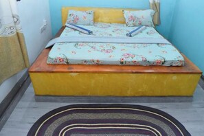 Una cama con ropa de cama floral, un cabecero de madera y una base amarilla.