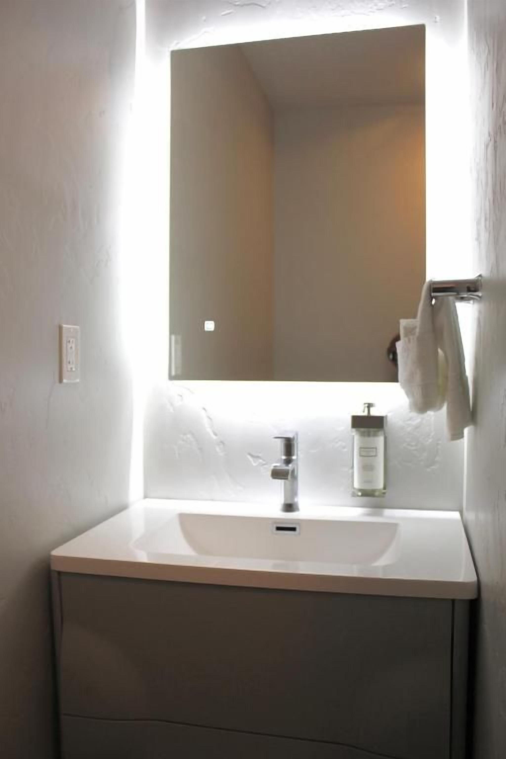 A bathroom with a white sink, a mirror, and a towel hanging on the wall.