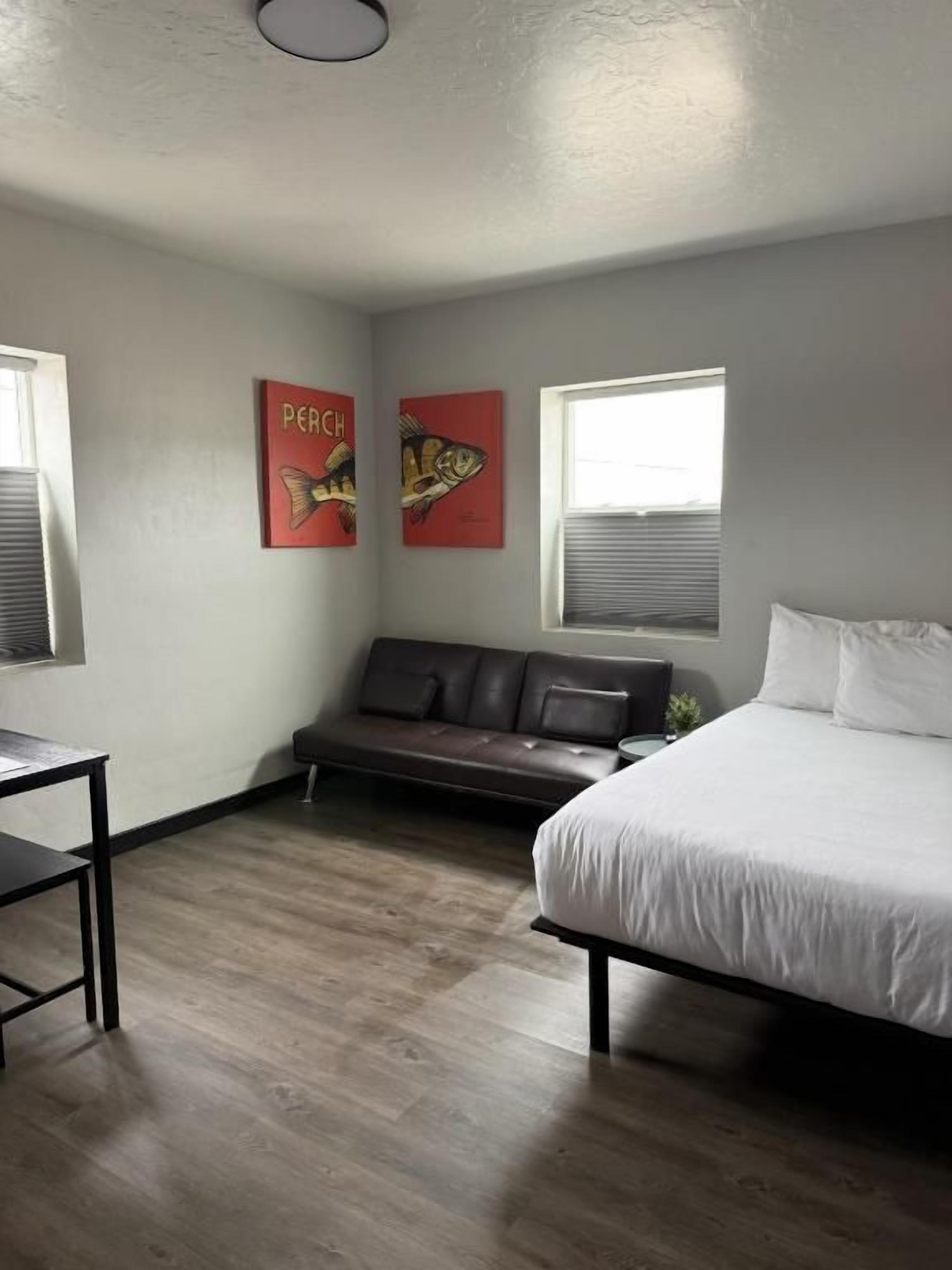 A bedroom with a bed, a sofa, a small table, and two wall-mounted artworks.