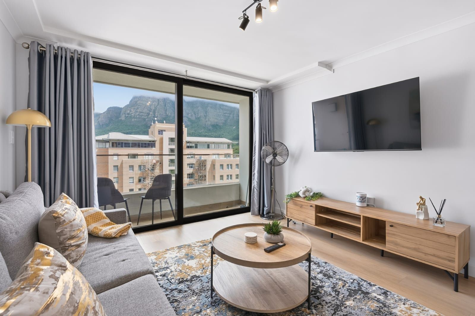 A modern living room with a sofa, a coffee table, and a TV mounted on the wall.