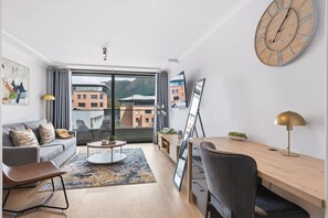 A modern living room with a sofa, coffee table, and a dining area with a table and chairs. - Newlands Peak 1 Bedroom Apartment (Cape Town)