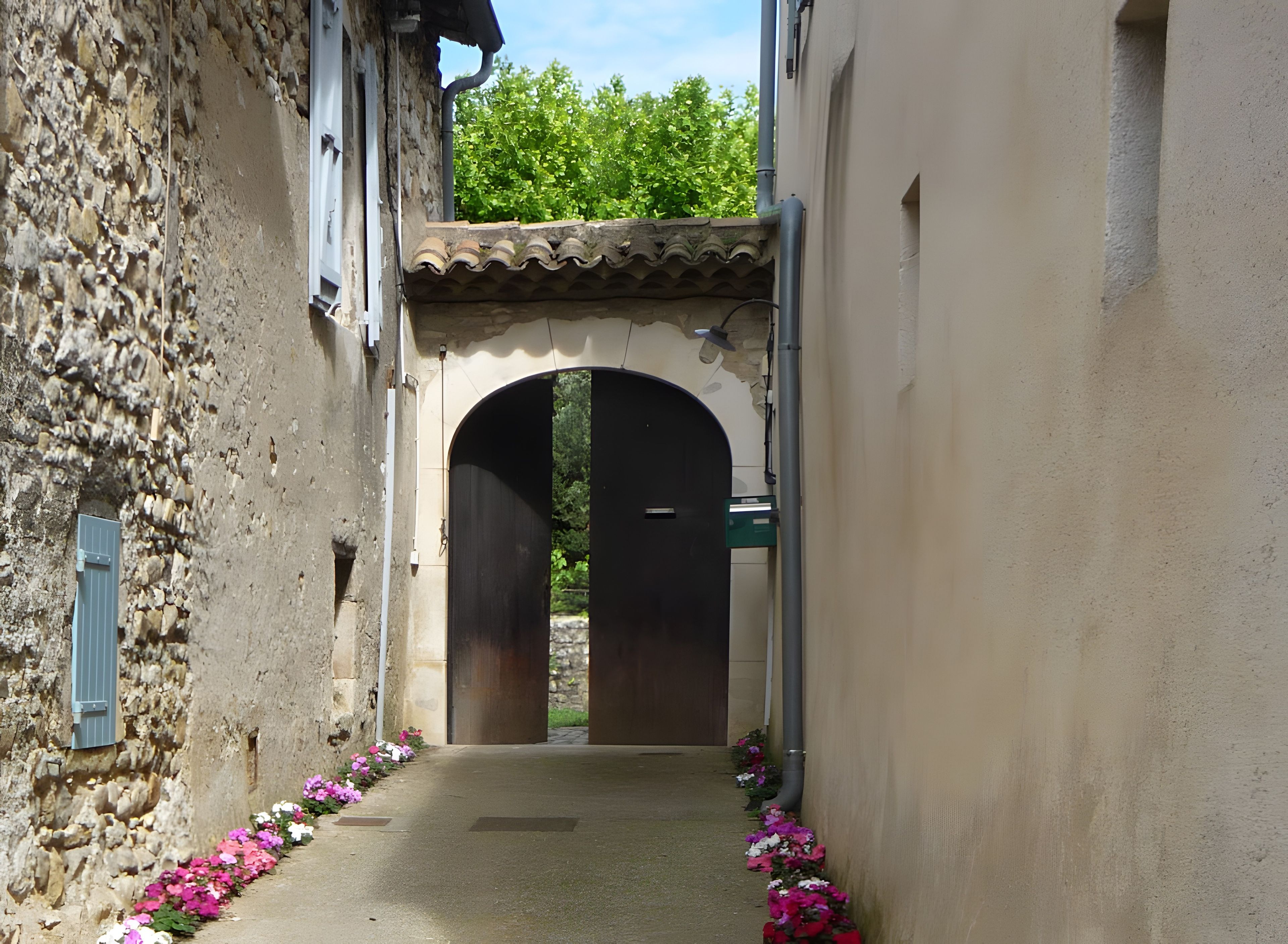 Un passage en arc, avec un mur de pierre d’un côté et un mur sobre de l’autre, menant à une entrée abritée.