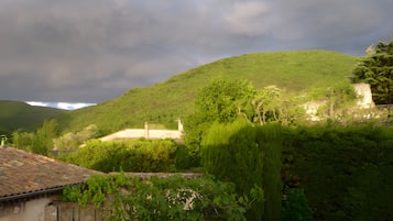 Un paysage rural avec une colline, de la verdure et un bâtiment doté d’un toit en tuiles.