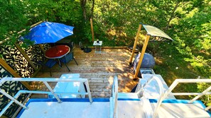 A wooden deck with a table and chairs, a blue umbrella, and a small table with a sign. - Peaceful Relaxation - Houseboat & Fall Foliage (Stone Mills)