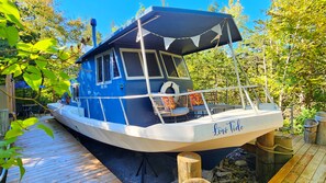A boat with a covered deck, a seating area with cushions, and a name 'Low Tide' on the side.