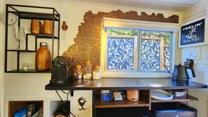 A kitchen counter with a coffee machine, a honeycomb wall decoration, and a window with a leaf pattern. - Peaceful Relaxation - Houseboat & Fall Foliage (Stone Mills)