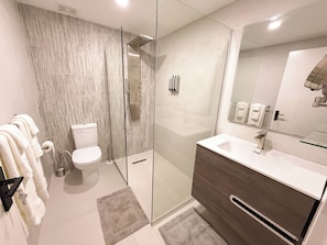 A modern bathroom with a glass-enclosed shower, a toilet, a vanity with a mirror, and a towel rack. - City Suite Walk 2 Beach Downtown CasaAmarilla301 (Oranjestad)
