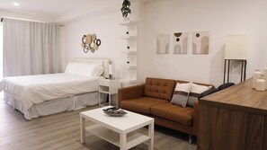 Una camera d'albergo moderna con un letto, una poltrona, un tavolino da caffè e una scrivania.