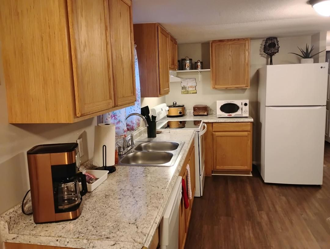 A kitchen with wooden cabinets, a coffee maker, a microwave, and a refrigerator.