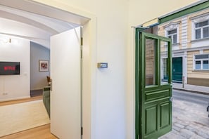 Ein Zimmer mit einer weißen Tür, einer grünen Tür, einem an der Wand montierten Fernseher und einem gerahmten Bild.