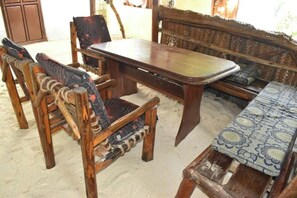 Un comedor de madera con sillas y una mesa, un sofá tejido y una alfombra estampada.