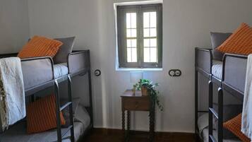 Una camera del dormitorio con letti a castello, un tavolino con lampada, una finestra e una lampada a sospensione.