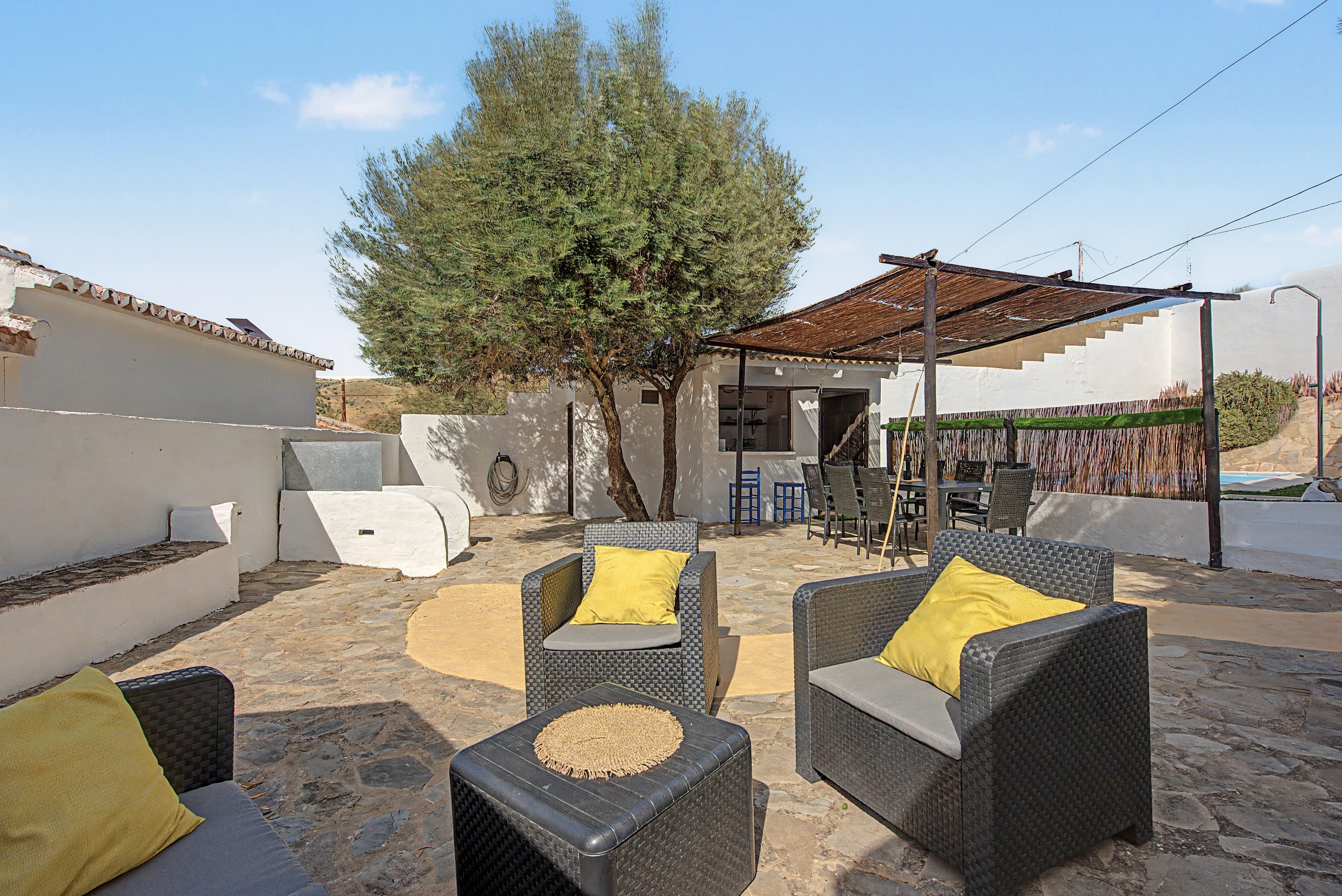 Un espacio de estar al aire libre con mobiliario de mimbre y una pérgola.