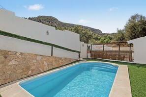 A swimming pool with a stone wall and a view of a mountainous landscape.