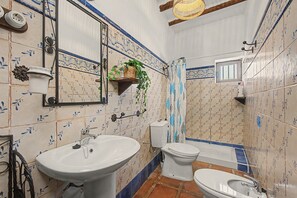 Un baño con lavamanos, inodoro y bañera, con azulejos de diseño floral.