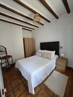 Une chambre à coucher comprenant un lit, une table de chevet, une commode et un luminaire suspendu.