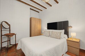 Un dormitorio con cama, mesitas de noche, un armario de madera y un espejo.