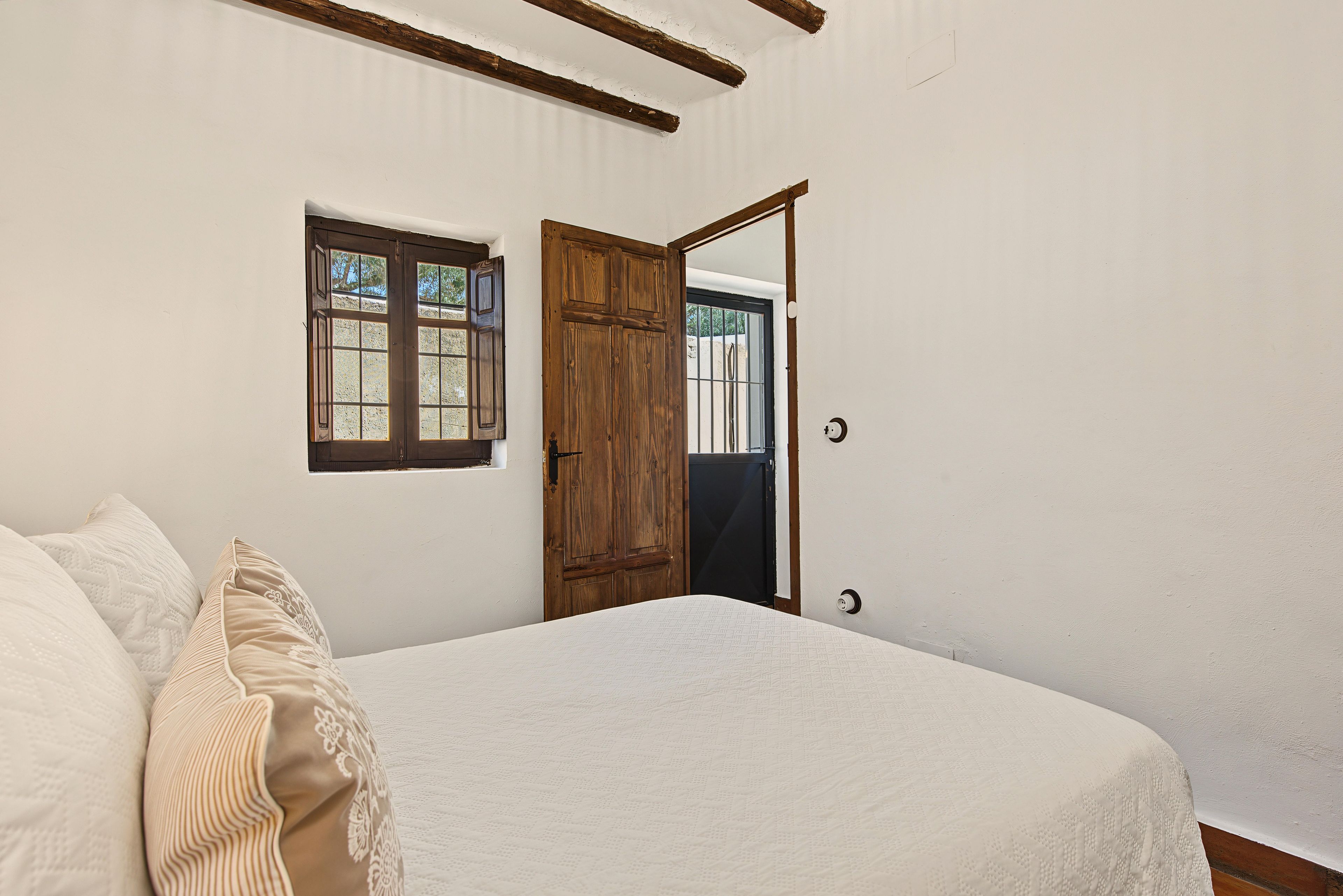 Un dormitorio con cama, ventana y puerta.
