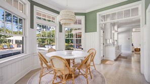 A dining area with a round table and wicker chairs, large windows, and a view of the outdoors. - Luxury Southold escape featuring a private pool, movie theater, gym, and... (Southold)