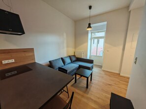 A modern living space with a wooden dining table, a sofa, and a pendant light. - Modern 1BR in trendy Žižkov (Praha 3)