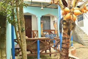 Een binnentuin met een palmboom, een houten tafel, stoelen en een blauw-wit gebouw.